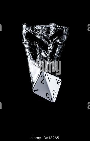 Black en white closeup photo of a D4 dice dropped in water with frozen motion, dark background and copy space Stock Photo