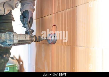 Construction worker using core drill and laser level on brick wall Stock Photo