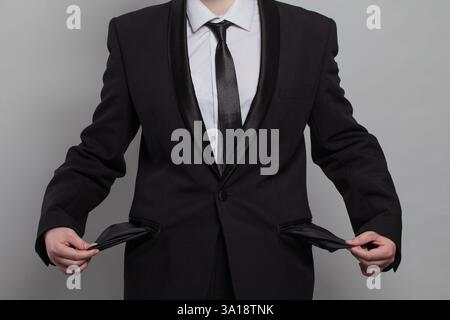 A man in a suit is showing his empty pockets. Concept of failed venture, bankruptsy. The formal attire of the suit Stock Photo