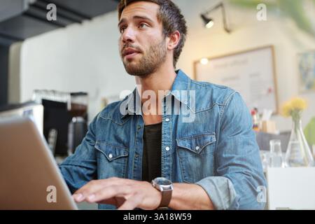 Business, man or thinking with laptop in cafe for online article, story development or creative process. Remote work, freelancer or thoughtful in Stock Photo