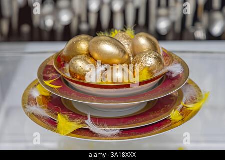 Bunch of Golden Eggs in Bowl Dish With Feathers Easter Decoration Stock Photo