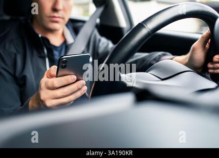 Driving distracted by phone. Car driver texting. Accident and crash danger. Man using mobile cellphone while on road. Irresponsible guy using text sms. Stock Photo