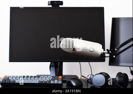 Large microphone on in front of computer screens on desk Stock Photo