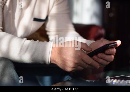 Man is sitting on a couch using mobile phone Stock Photo