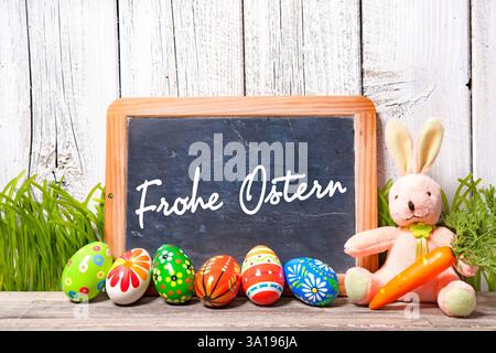 Background for Eater with german text. Easter decoration with sugar rabbit, eggs and message board Stock Photo