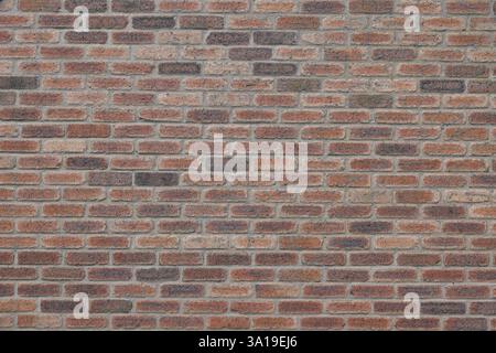 A brick wall with a brown and tan color. The wall is made of bricks and has a rough texture Stock Photo