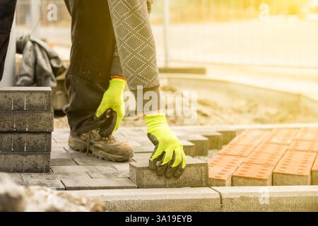 Construction worker carefully placing paving slabs for a new driveway Stock Photo