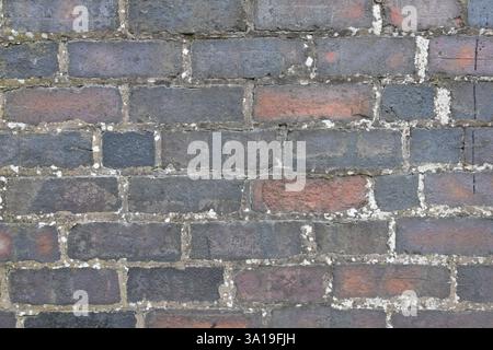 A brick wall with a gray and red color. The wall is made of bricks and has a rough texture Stock Photo