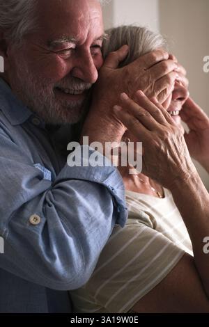 Elderly husband surprises his mature wife by covering her eyes with his