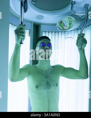 Young Thin Man At Solarium In Beauty Salon. Shower for full tan. Stock Photo
