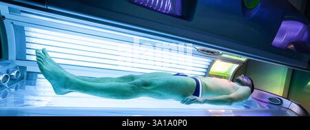 Young Thin Man At Solarium In Beauty Salon. Full tanning bed. Stock Photo
