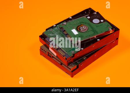 A stack of computer hard disk drives on orange background Stock Photo