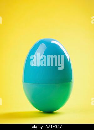 Blue plastic egg close up on yellow background. Stock Photo