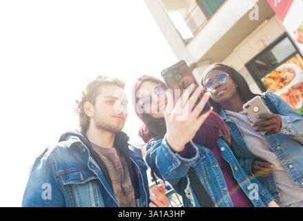 Multiracial friends taking selfie outdoors. Happy friendship concept with young students having fun together Stock Photo
