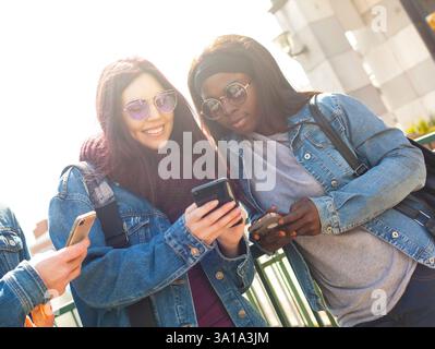 Multiracial friends having fun with smartphone in a spring day. Stock Photo