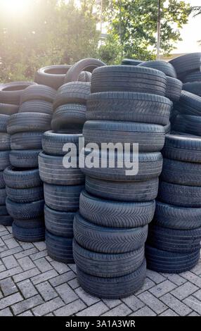 Many old tires are stacked on top of each other, waiting to be recycled or processed Stock Photo