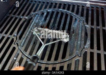 Dirty barbecue grill is being cleaned with a wire brush Stock Photo