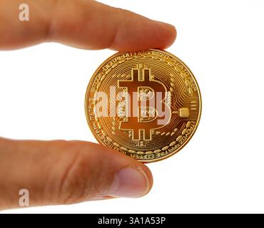 A Bitcoin coin between the fingers. Subject isolated on white background. Stock Photo