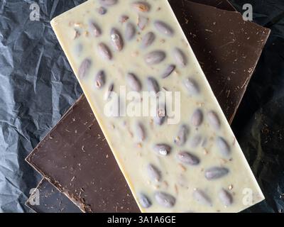 stack of chocolate bars, white almond bars on black paper , flat lay Stock Photo