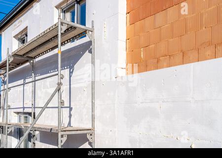Workers installing external thermal insulation with scaffolding on residential building Stock Photo