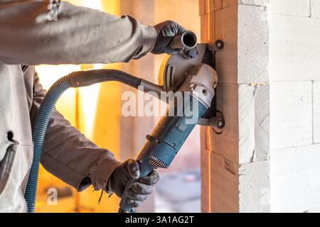 Construction worker cutting aerated concrete block wall using circular saw with vacuum dust extraction Stock Photo