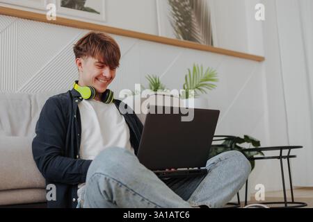 Happy young entrepreneur feeling excited about new project while working on laptop at home. Stock Photo