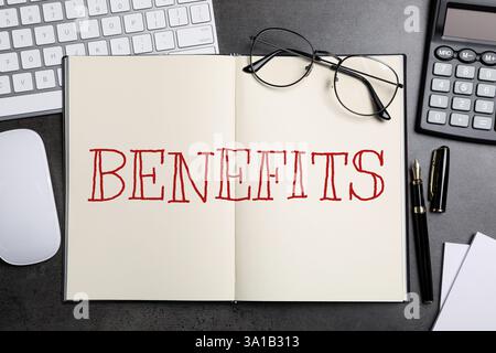 Benefits word in notebook, calculator, eyeglasses, pen, computer keyboard and mouse on black table, top view Stock Photo