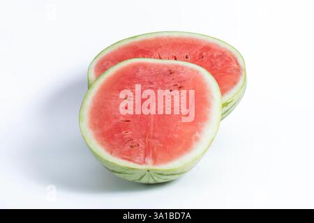 A fresh ripe watermelon cut in half and displayed on a white background, showing off its vibrant red interior and green exterior. Stock Photo