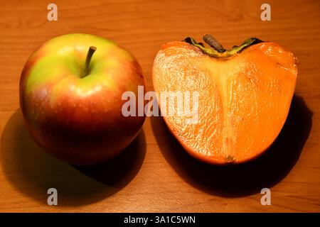 Healthy food. Top view of sliced ingredients for fruit salad or snack - apple, pear, nuts, persimmon. Flat lay, copy space on wood Stock Photo