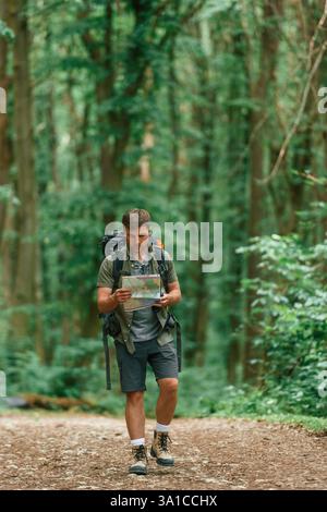 Walking forward with map in hands. Tourist in summer forest. Conception of exploration and leisure. Stock Photo