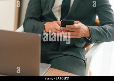 Close up view of businessman that is sitting and using smartphone. Stock Photo