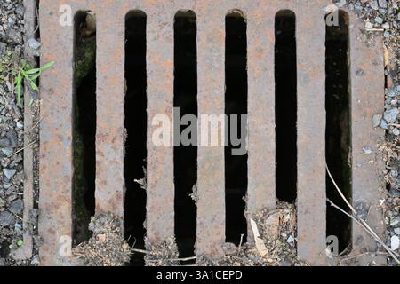 A rusty grate with holes in it. The holes are in a row. The grate is dirty Stock Photo