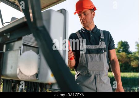 Checking the temperature by thermal imager. Man is doing operating and maintenance in solar power plant. Stock Photo