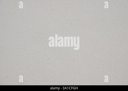 A white wall with a rough texture. The wall is covered in small bumps and ridges, giving it a somewhat uneven appearance. The texture of the wall is n Stock Photo