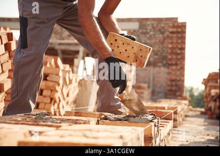With brick in hands. Close up view of man that is working on the construction site. Stock Photo