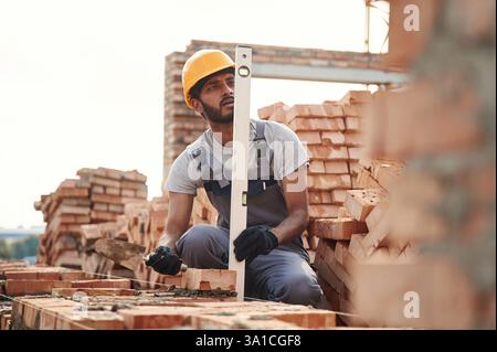 Using the leveler. Handsome Indian man is on the construction site. Stock Photo