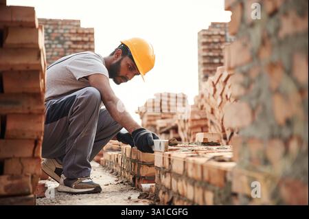 Using the leveler. Handsome Indian man is on the construction site. Stock Photo