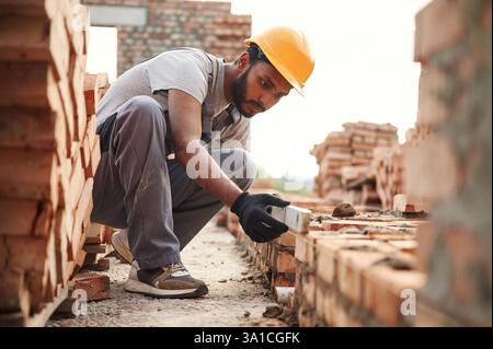 Using the leveler. Handsome Indian man is on the construction site. Stock Photo