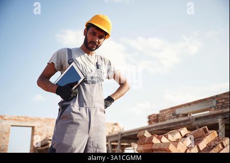 Manager with digital tablet. Handsome Indian man is on the construction site. Stock Photo