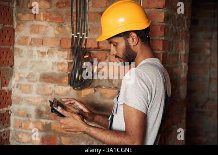 Digital tablet in hands. Handsome Indian man is on the construction site. Stock Photo