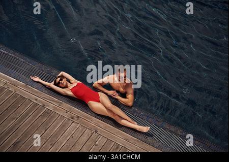Woman is lying down. Man is in the pool. Stock Photo