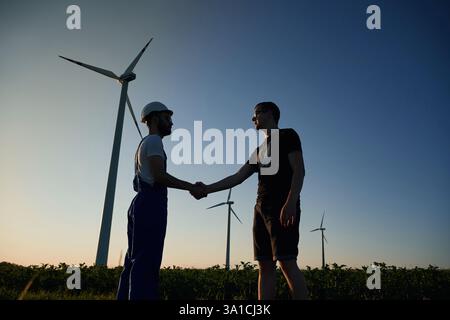 Making deal with businessman. Service engineer is on the field with windmills. Stock Photo