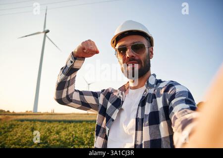 Making selfie. Service engineer is on the field with windmills. Stock Photo