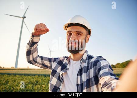 Making selfie. Service engineer is on the field with windmills. Stock Photo
