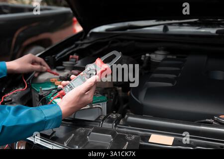 Mechanic uses multimeter to check car battery Stock Photo