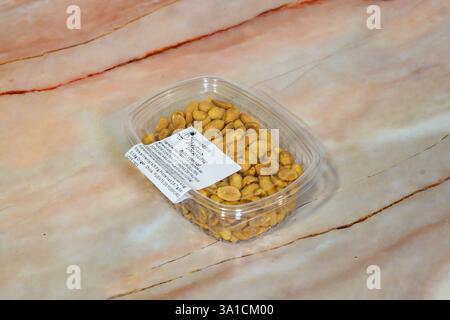 A bag of peanuts sits on a marble countertop. The peanuts are in a clear plastic container Stock Photo