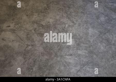 A grey and dirty floor with a few scratches and marks. The floor is made of concrete and has a rough texture Stock Photo