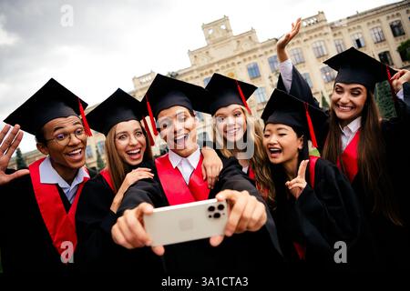 Joyful university graduates taking a celebratory selfie outside on campus Stock Photo