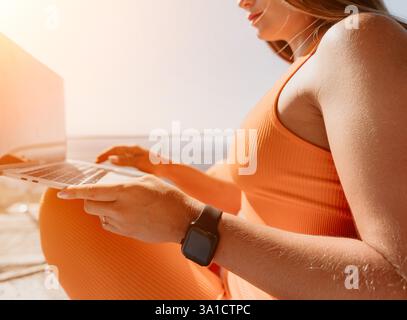 Woman in Orange Outfit Using Laptop on a Sunny Day Stock Photo