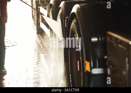Man is washing the big vehicle indoors. Close up view. Stock Photo